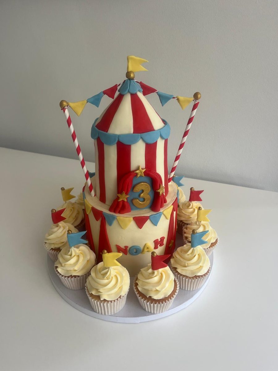 Two tier circus big top cake with bunting, flags and matching cupcakes